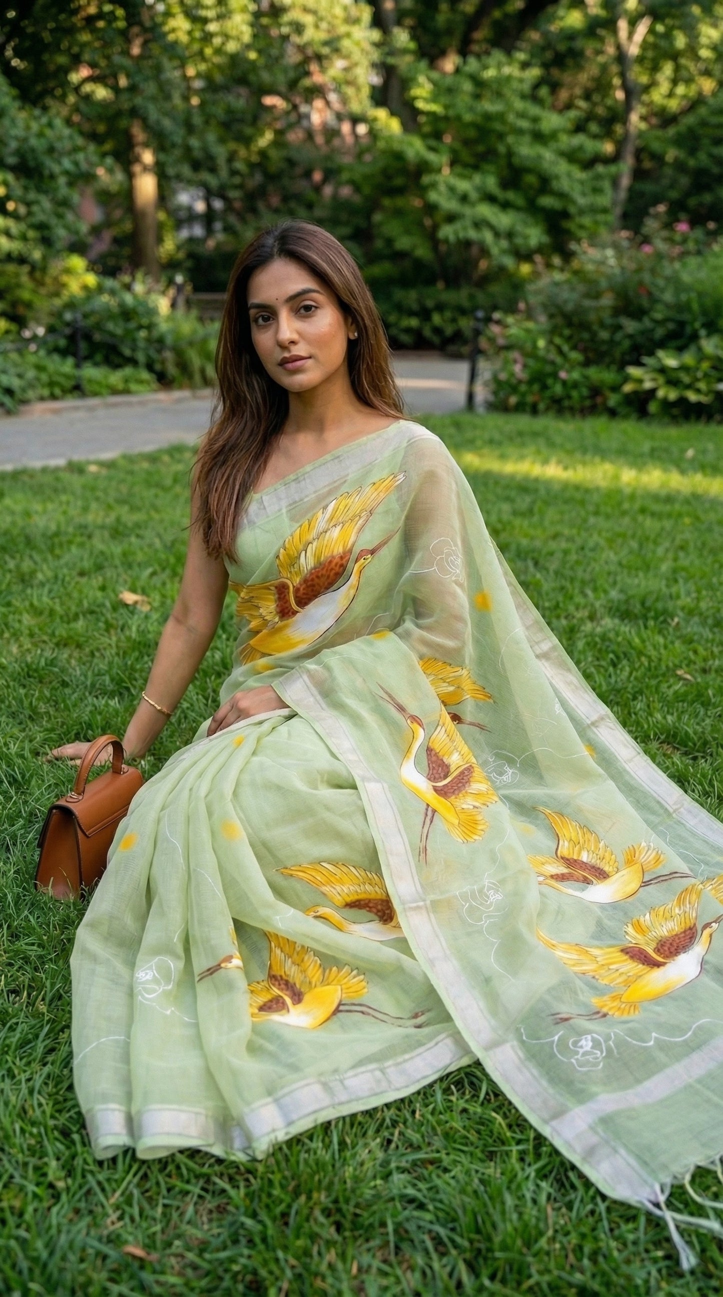 Woman in a light-green-kota-doria-crane-saree, sitting on grass