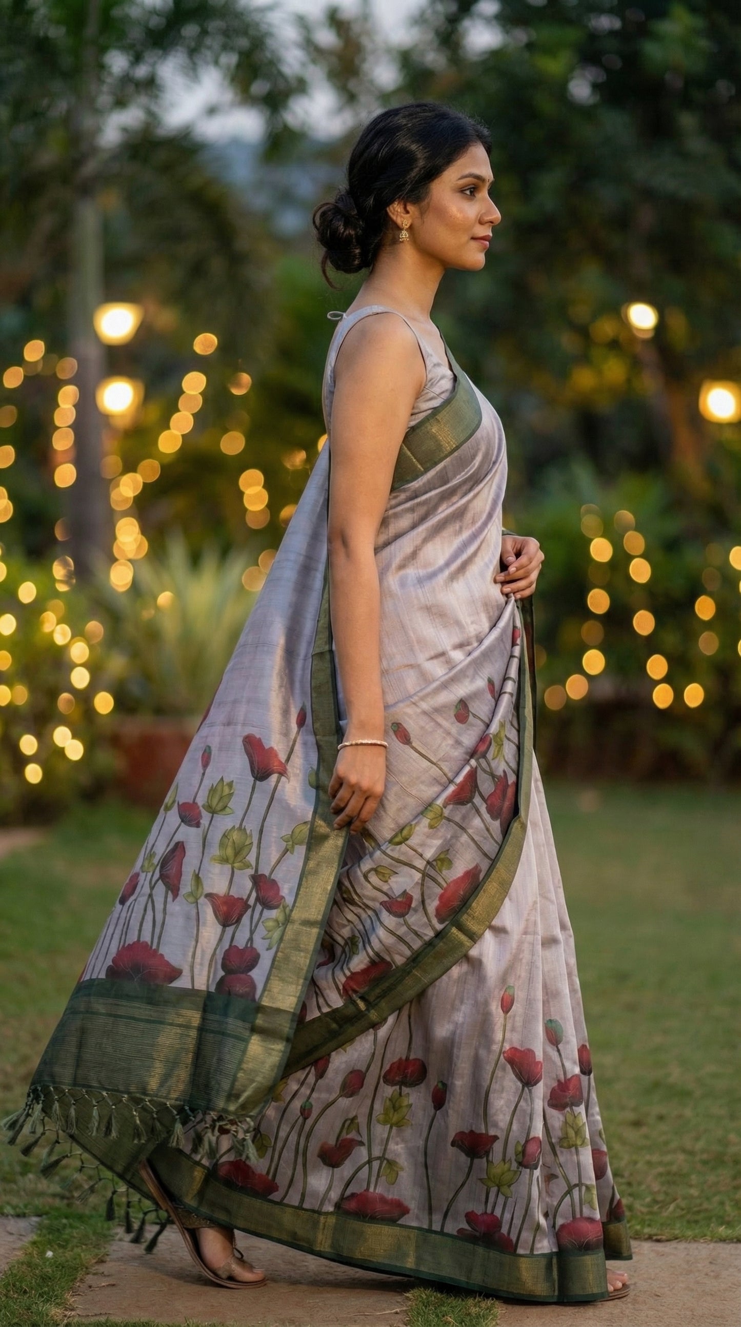 Woman in a light-pink-viscose-silk-floral-saree, standing outdoors with decorative lights in the background