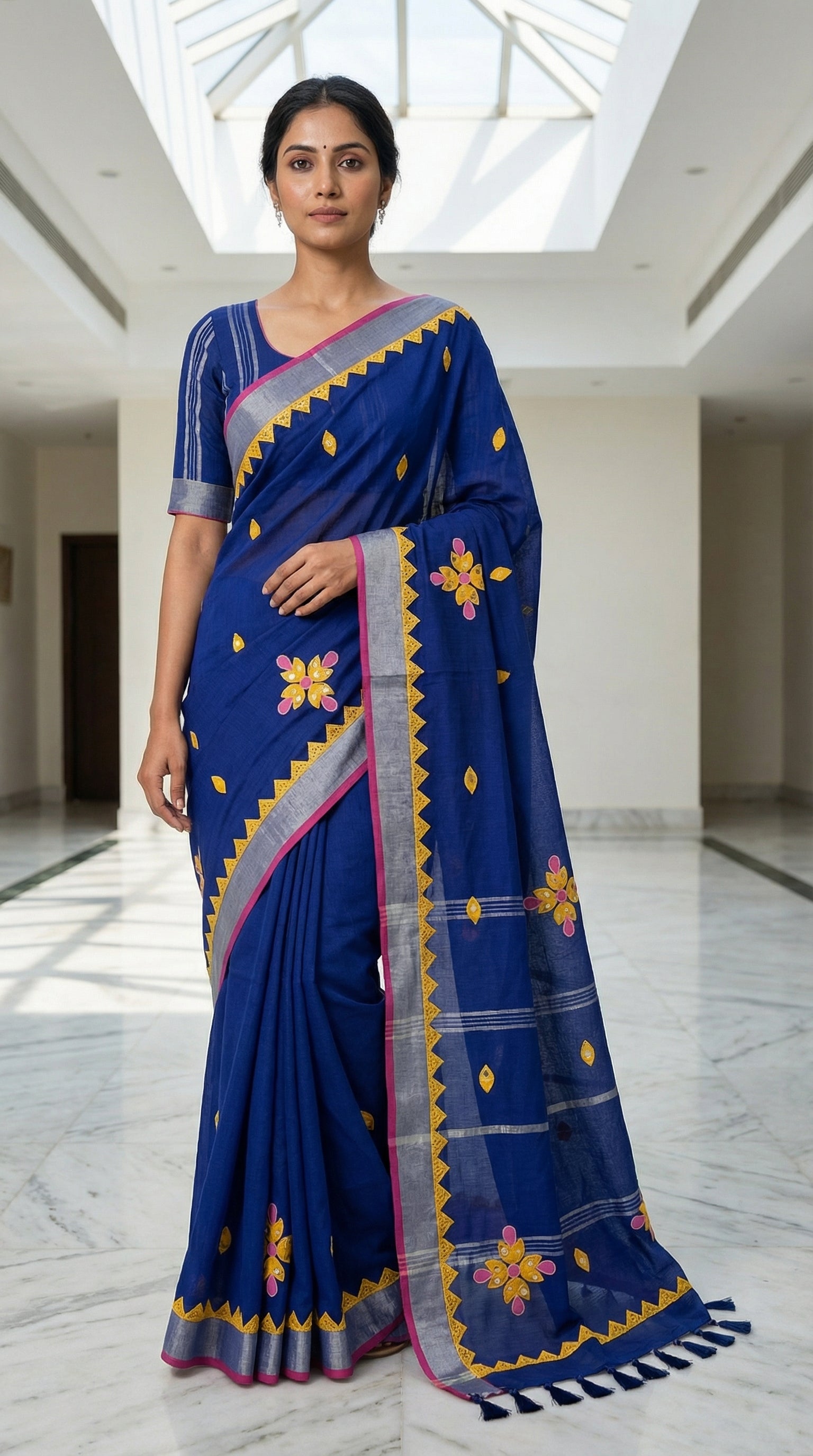 Navy linen cotton saree with multicolor floral appliqué and hand embroidery, artisan-crafted traditional Indian saree, with floral patterns in an indoor setting.