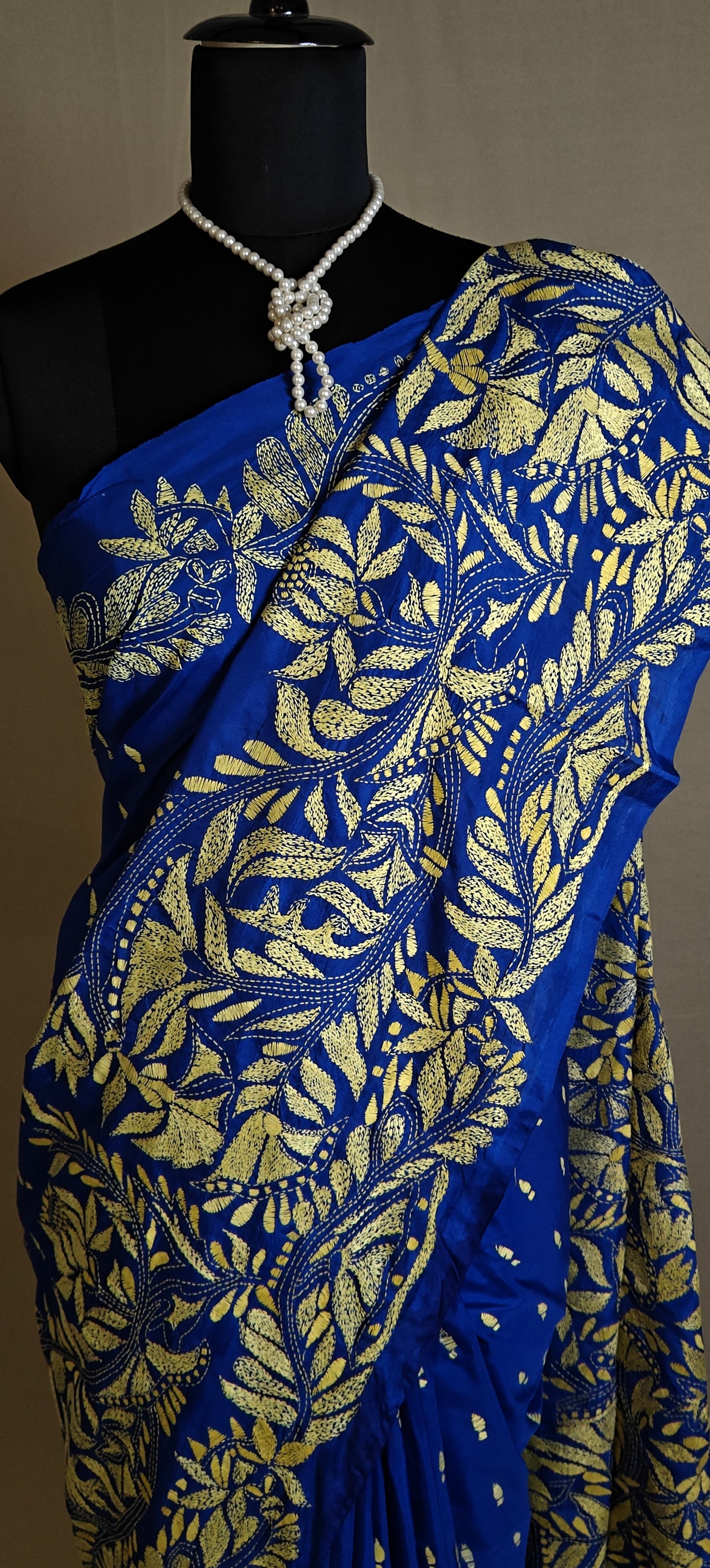 Luxury Kantha-Stitched Silk Saree – Royal Blue with Golden Floral Embroidery saree with gold leaf patterns on a mannequin against a neutral background.