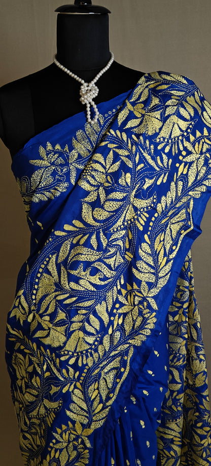 Luxury Kantha-Stitched Silk Saree – Royal Blue with Golden Floral Embroidery saree with gold leaf patterns on a mannequin against a neutral background.