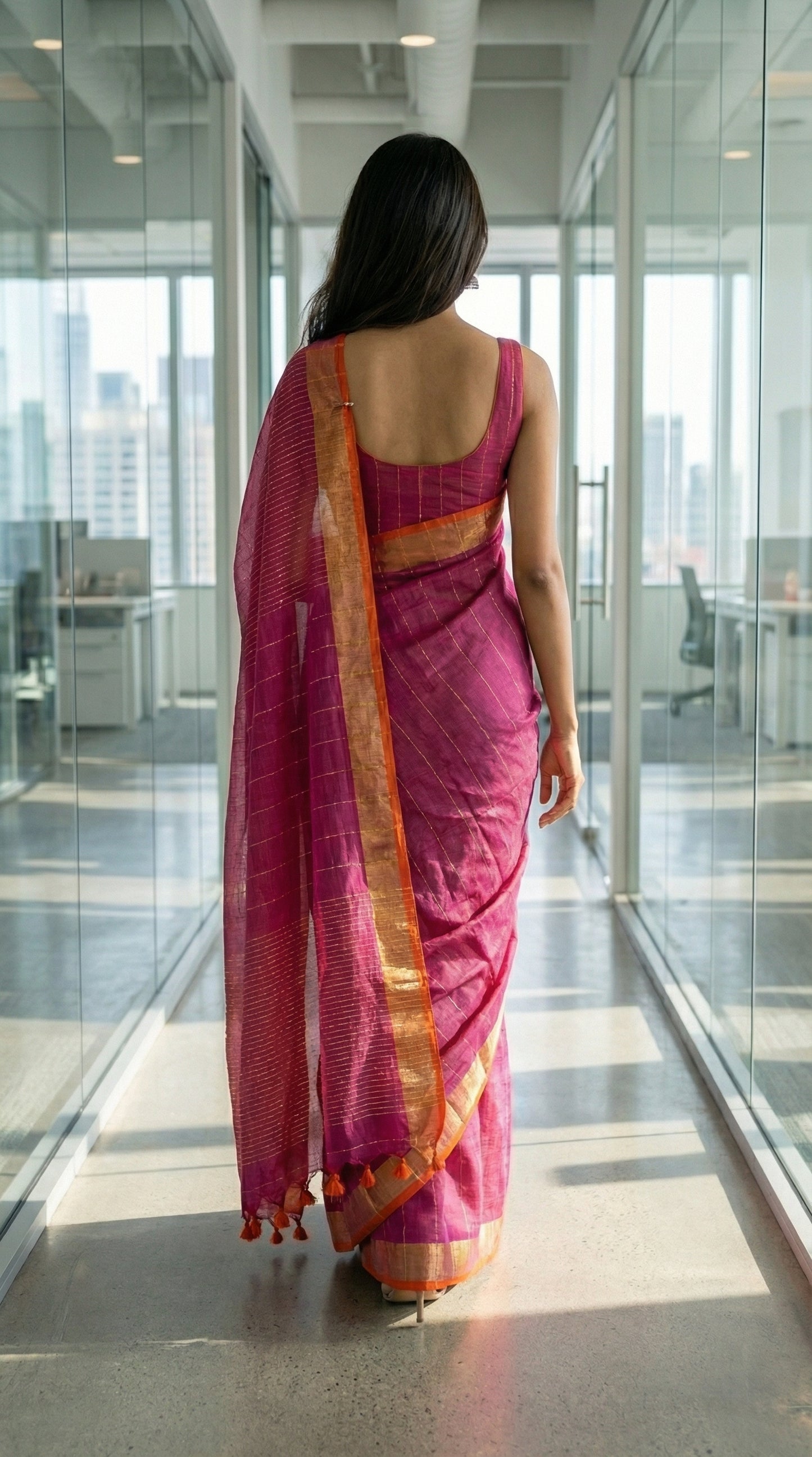 Woman in a magenta-cotton-linen-saree-Zari, walking in an office building.