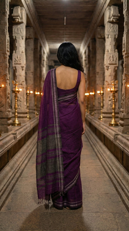 Woman in a magenta-mul-cotton-saree, walking through a temple corridor.