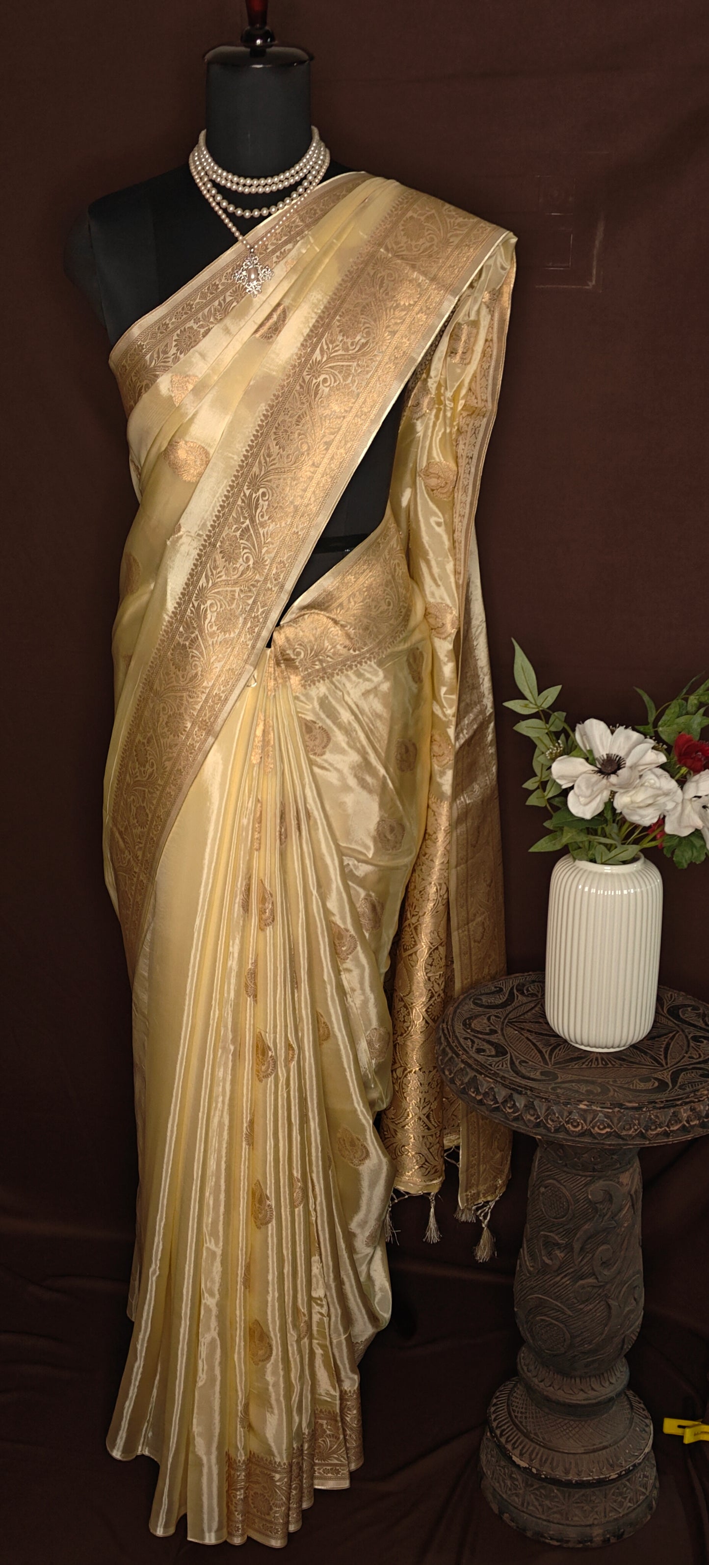 Beige Mashru silk saree with golden embroidery and pearl accessories on mannequin.