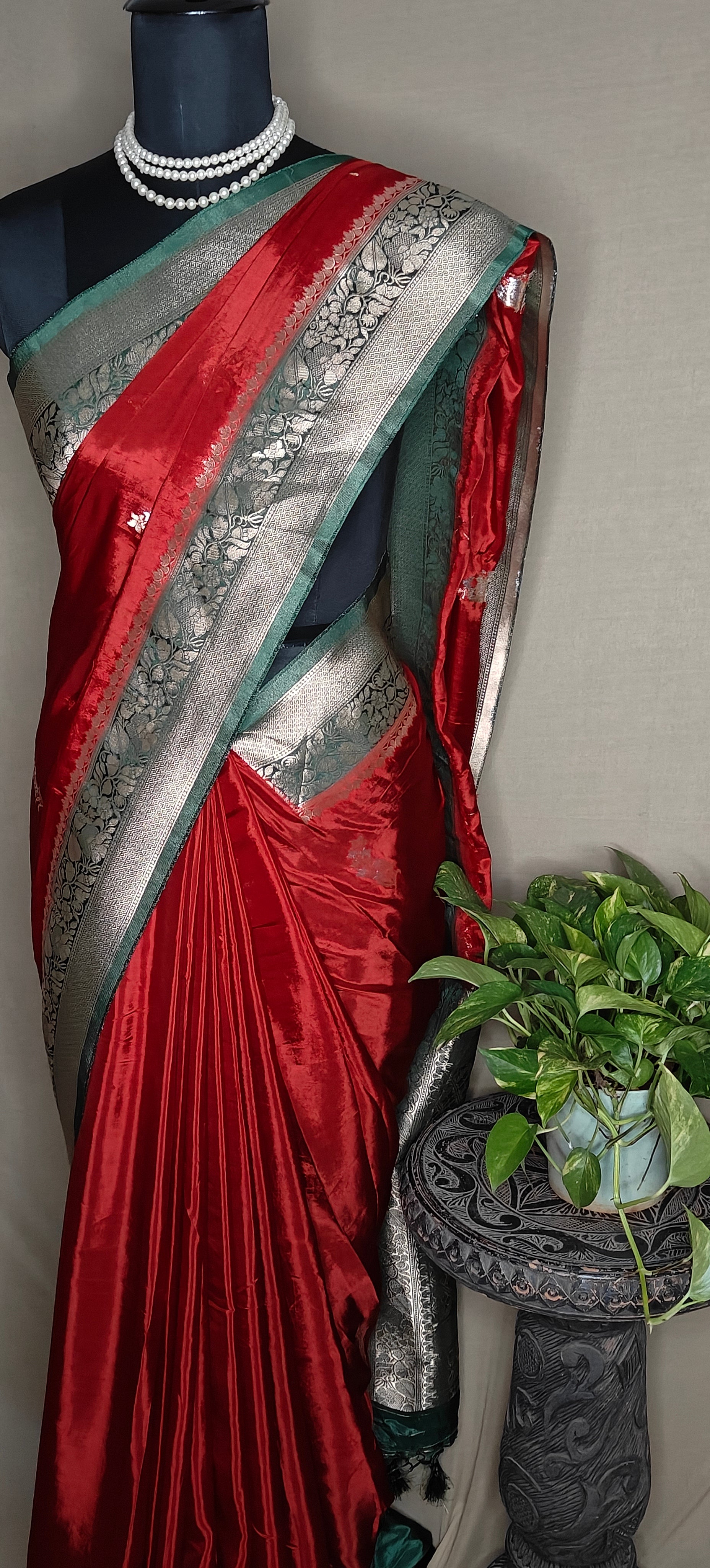Red Mashru silk saree with silver-green floral border, displayed on mannequin.