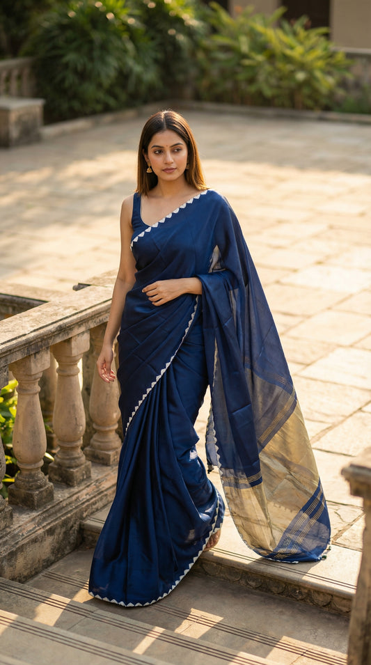 Woman in a blue Modal Silk Saree with Lagdi Patta Pallu saree with white border, standing outdoors on a stone path.