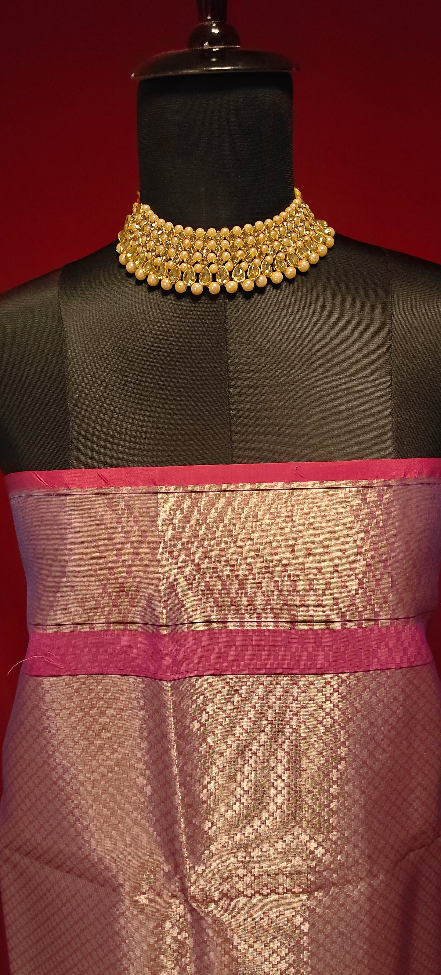 Purple muslin silk brocade blouse piece with zari border styled on mannequin against a red background.