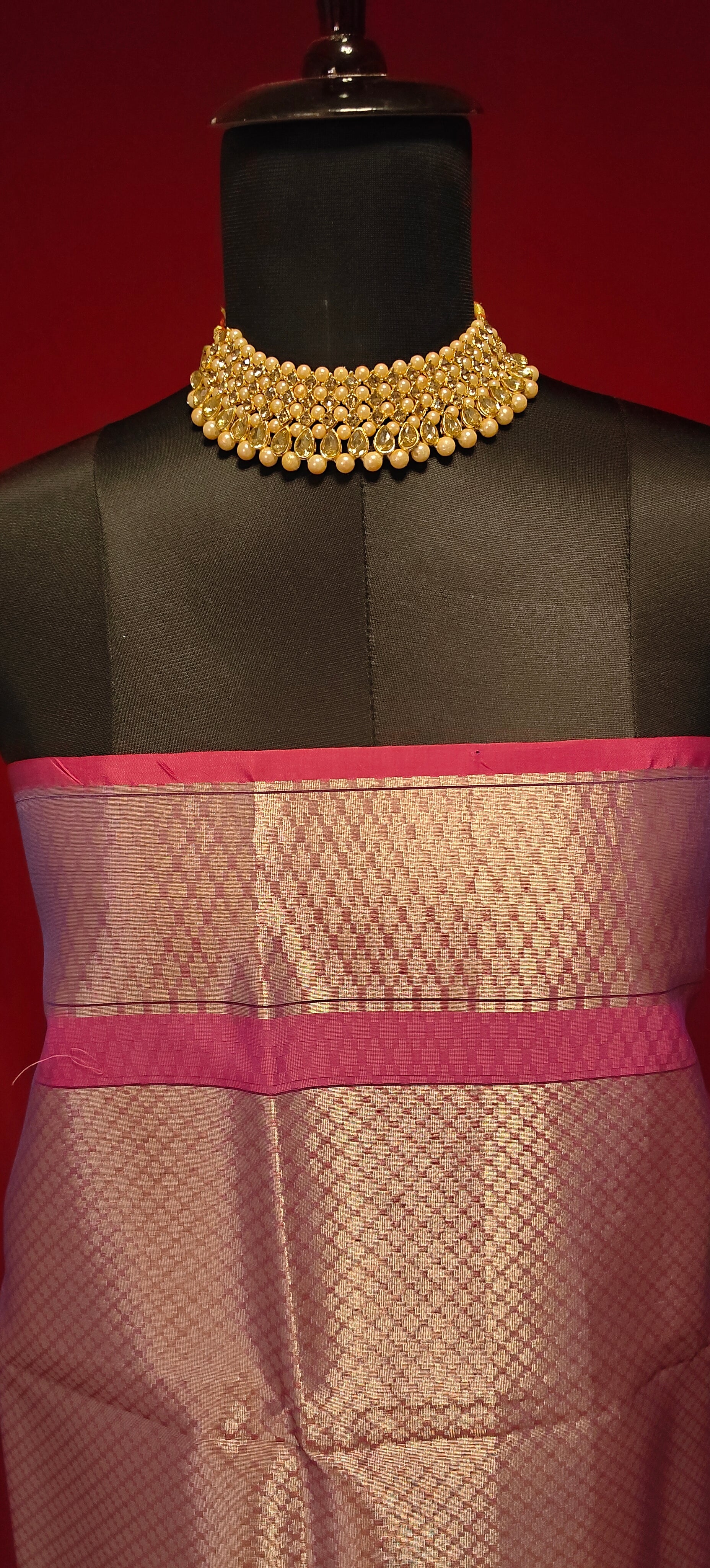 Purple muslin silk brocade blouse piece with zari border styled on mannequin against a red background.