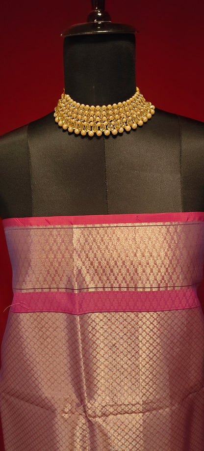 Purple muslin silk brocade blouse piece with zari border styled on mannequin against a red background.