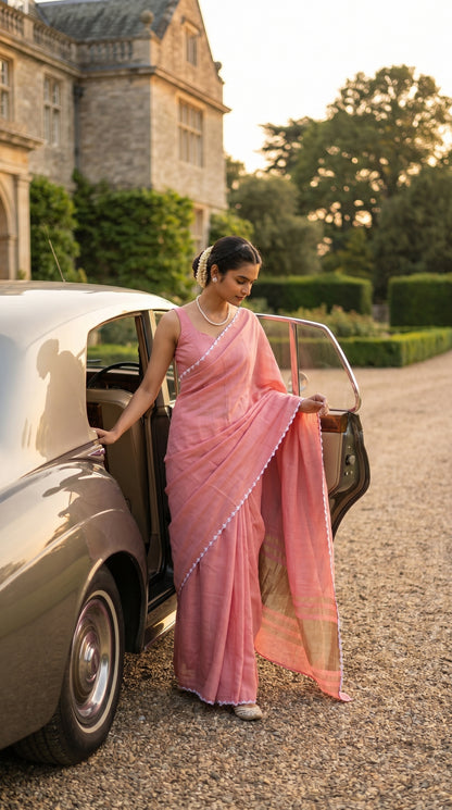 Woman in a pink saree getting out of a vintage car in a driveway.