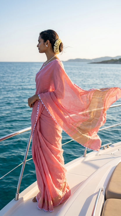 Woman in a pink saree standing on a boat with ocean and sky in the background