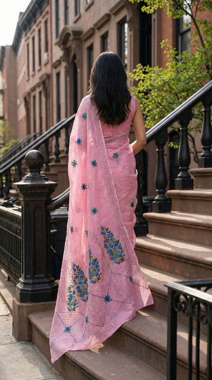 Woman in a pink-chanderi-kantha-saree, walking up steps in an urban setting.