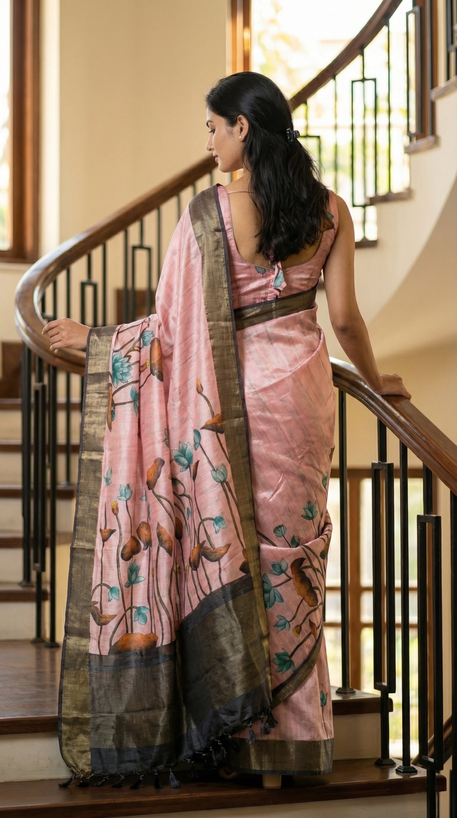 Woman in a pink-viscose-silk-grey-floral-saree, standing on a staircase.