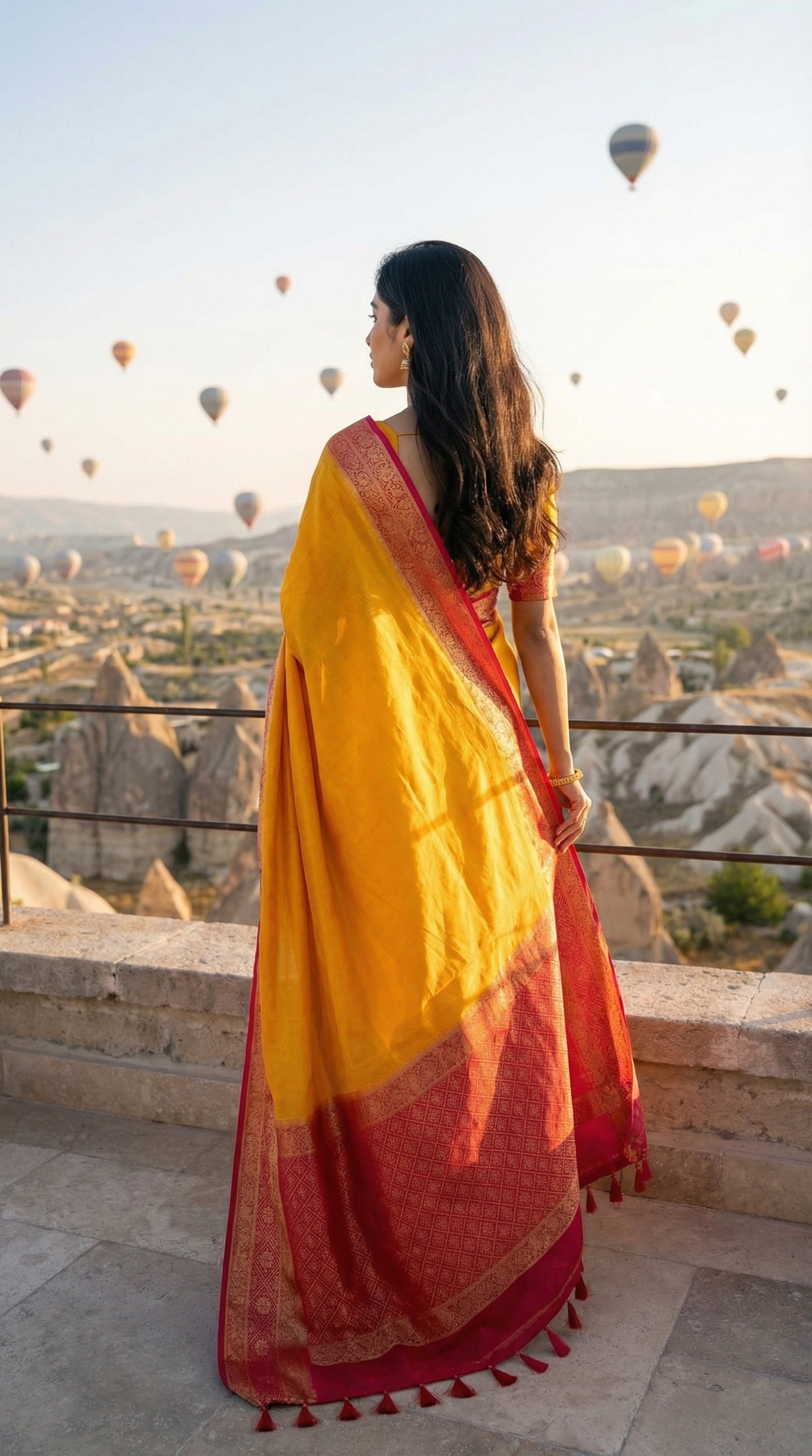 Woman in a bright yellow Pochampally silk saree with geometric ikat patterns and rich gold Zari border, overlooking hot air balloons in Cappadocia.