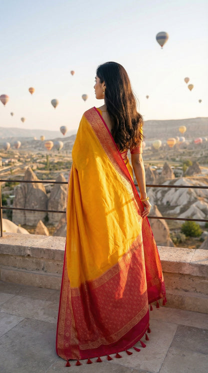 Woman in a bright yellow Pochampally silk saree with geometric ikat patterns and rich gold Zari border, overlooking hot air balloons in Cappadocia.