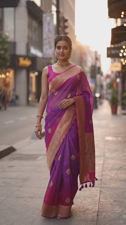 A full-length front portrait of a woman walking gracefully on a street and taking a swirl, beautifully displaying the structured royal drape, golden buttis, and detailed pink zari border of her purple handloom saree