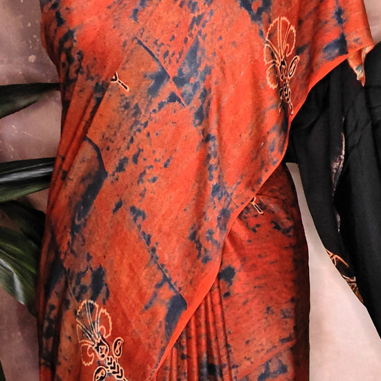 Ajrakh Modal Silk Saree – Red & Black Tie-Dye with Black Pallu saree with floral patterns on a mannequin against a decorative background.