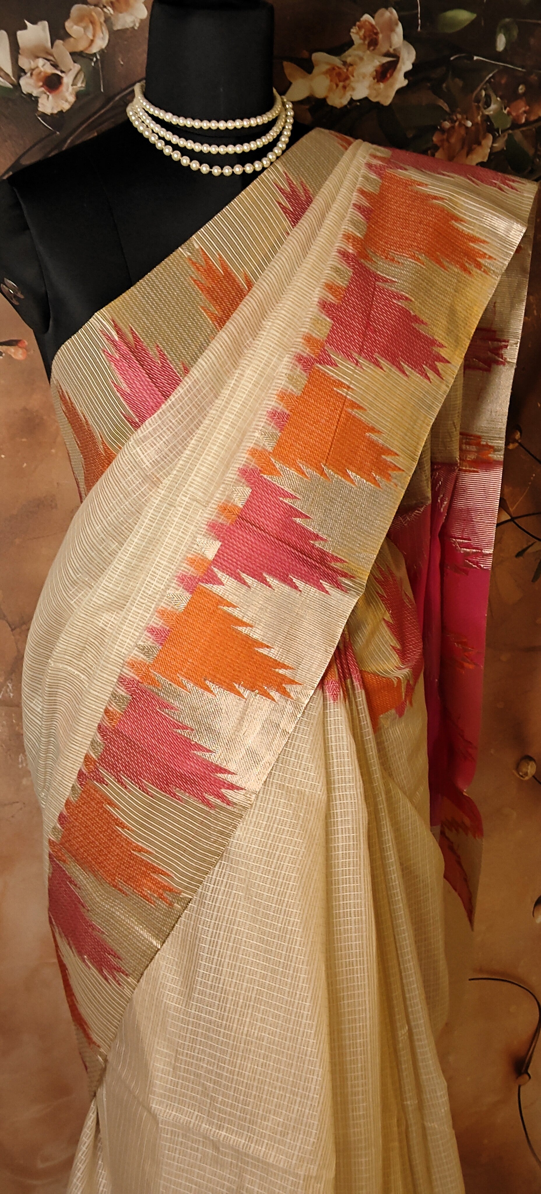 Kota Blend Saree – Cream Base with Vibrant Zigzag Pallu saree on a mannequin against a floral background.