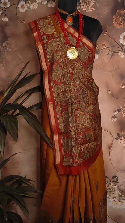 Maroon blended silk saree with Kalamkari-inspired floral and paisley digital print and broad golden border on a mannequin against a floral background.