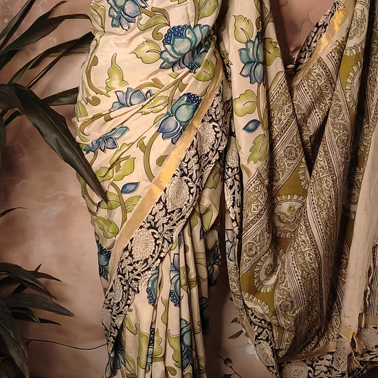 Kalamkari Print Silk Saree – Cream with Blue-Green Floral Motifs and Zari Border draped on a mannequin.