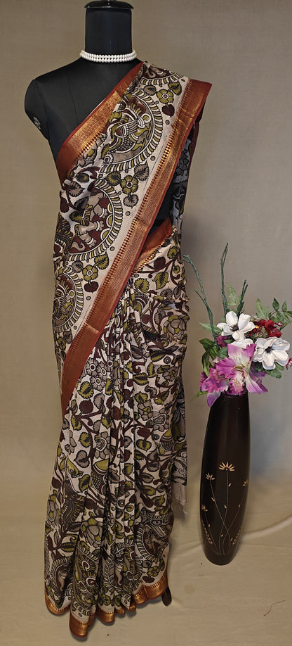 Brown silk saree with Kalamkari-inspired motifs and subtle golden border on a mannequin wearing a pearl necklace, against a neutral background.