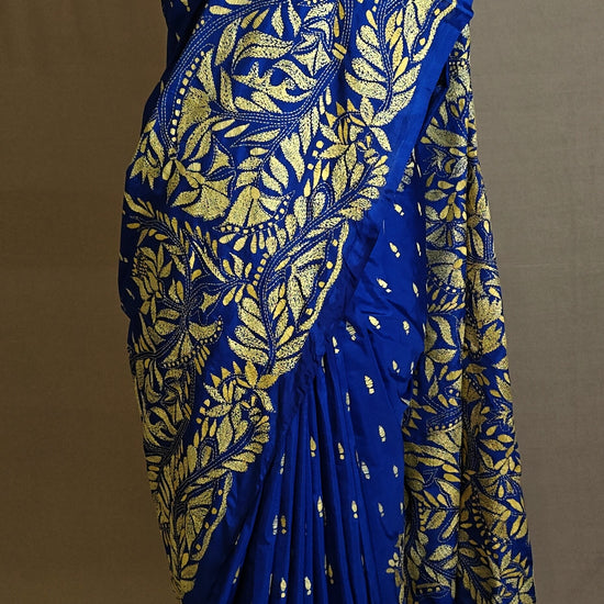 Luxury Kantha-Stitched Silk Saree – Royal Blue with Golden Floral Embroidery saree with gold leaf patterns on a mannequin against a neutral background.