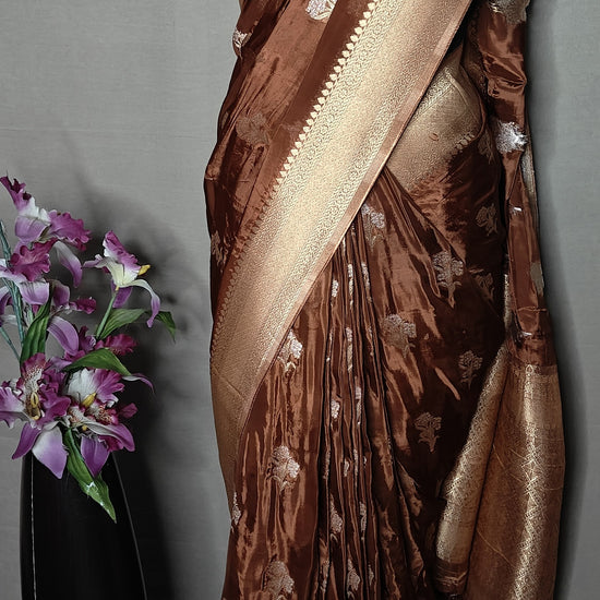 Copper-brown and beige Mashru silk saree with floral embroidery, displayed flat with decor accents