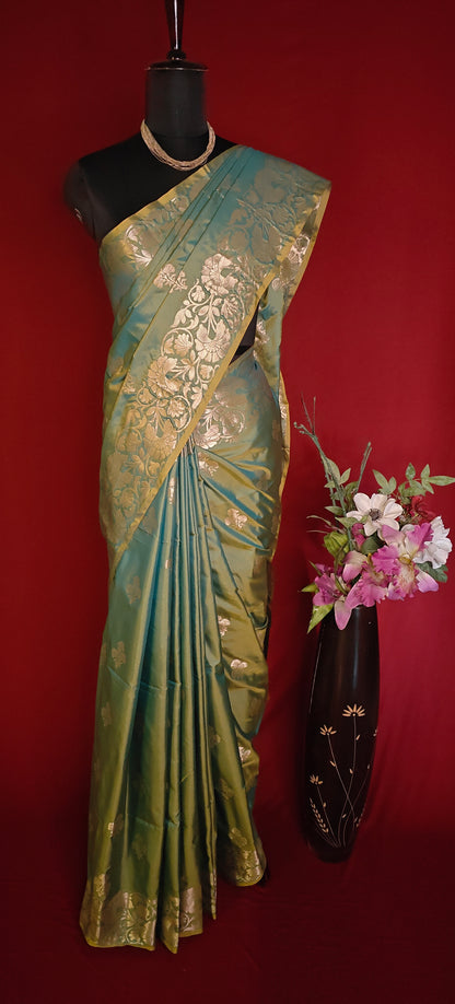 Emerald green silk blend saree with intricate woven detailing and elegant drape on a mannequin with a red background