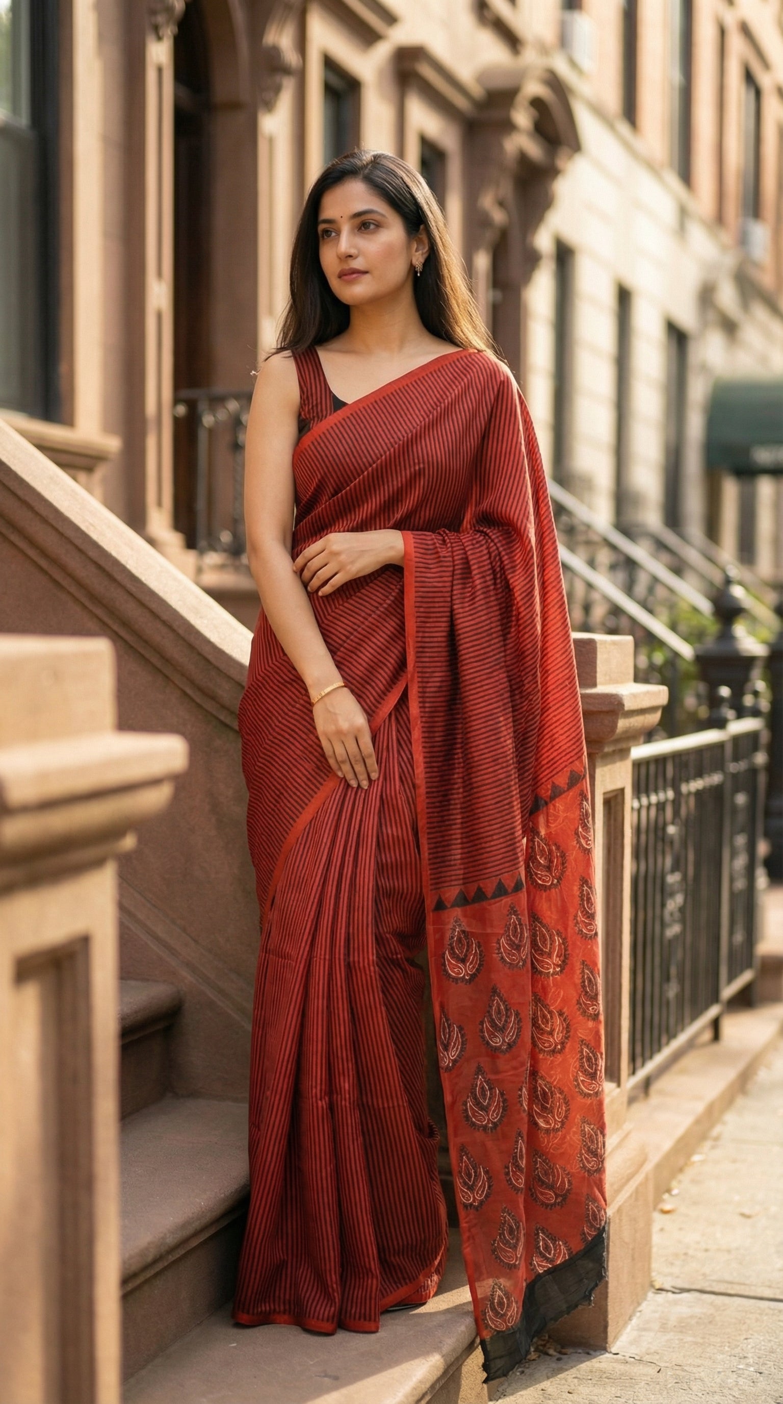 Woman in a red pure modal silk saree with traditional Ajrakh print, standing on a city street.