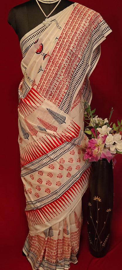 Pure Bishnupuri silk saree in white with red and black printed motifs inspired by traditional Indian art on a mannequin showcasing saree pallu with flower vase against a red background.