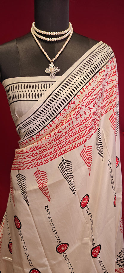 Pure Bishnupuri silk saree in white with red and black printed motifs inspired by traditional Indian art on a mannequin showcasing blouse piece against a red background.