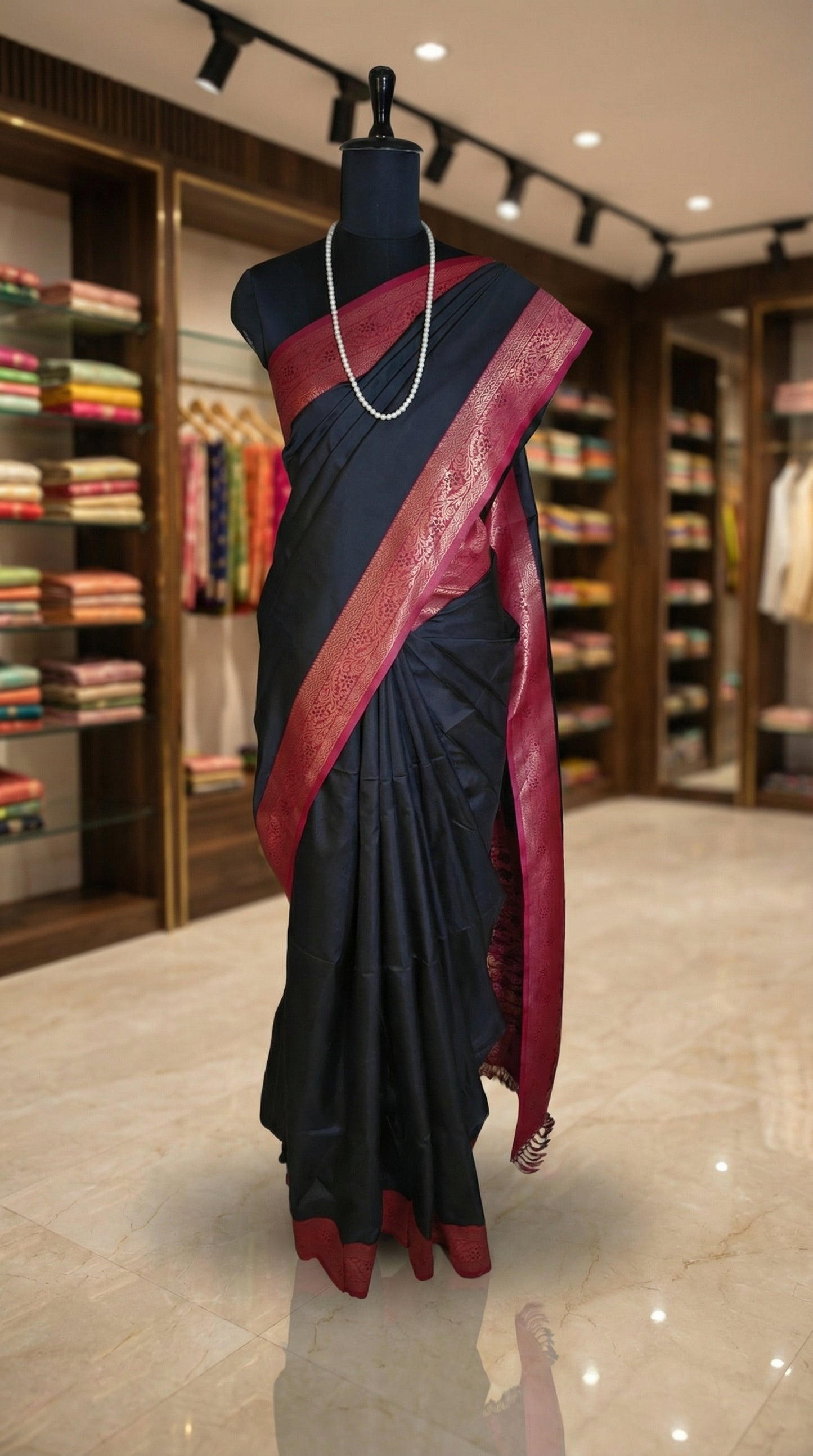 Black pure soft silk saree with magenta zari border and golden motifs showcased on a mannequin inside a retail store.