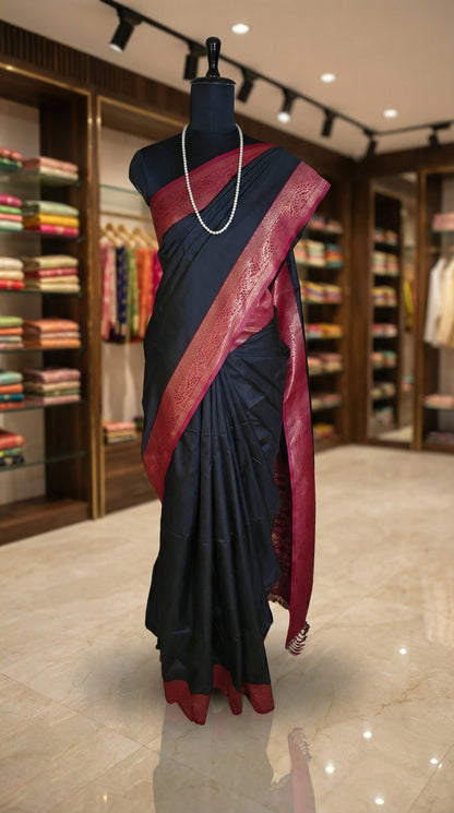 Black pure soft silk saree with magenta zari border and golden motifs showcased on a mannequin inside a retail store.
