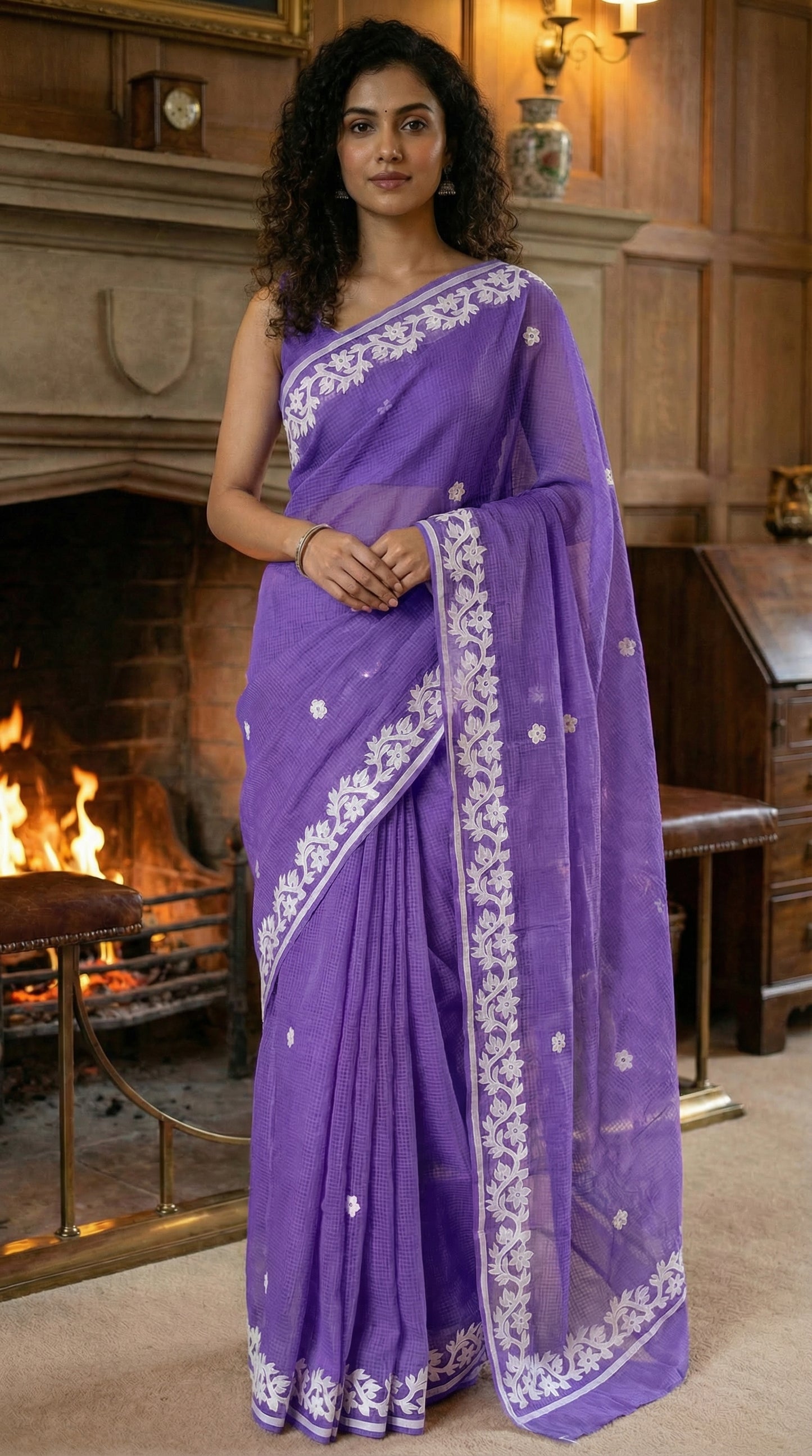 Woman in a purple-kota-doria-saree, in a room with a fireplace.