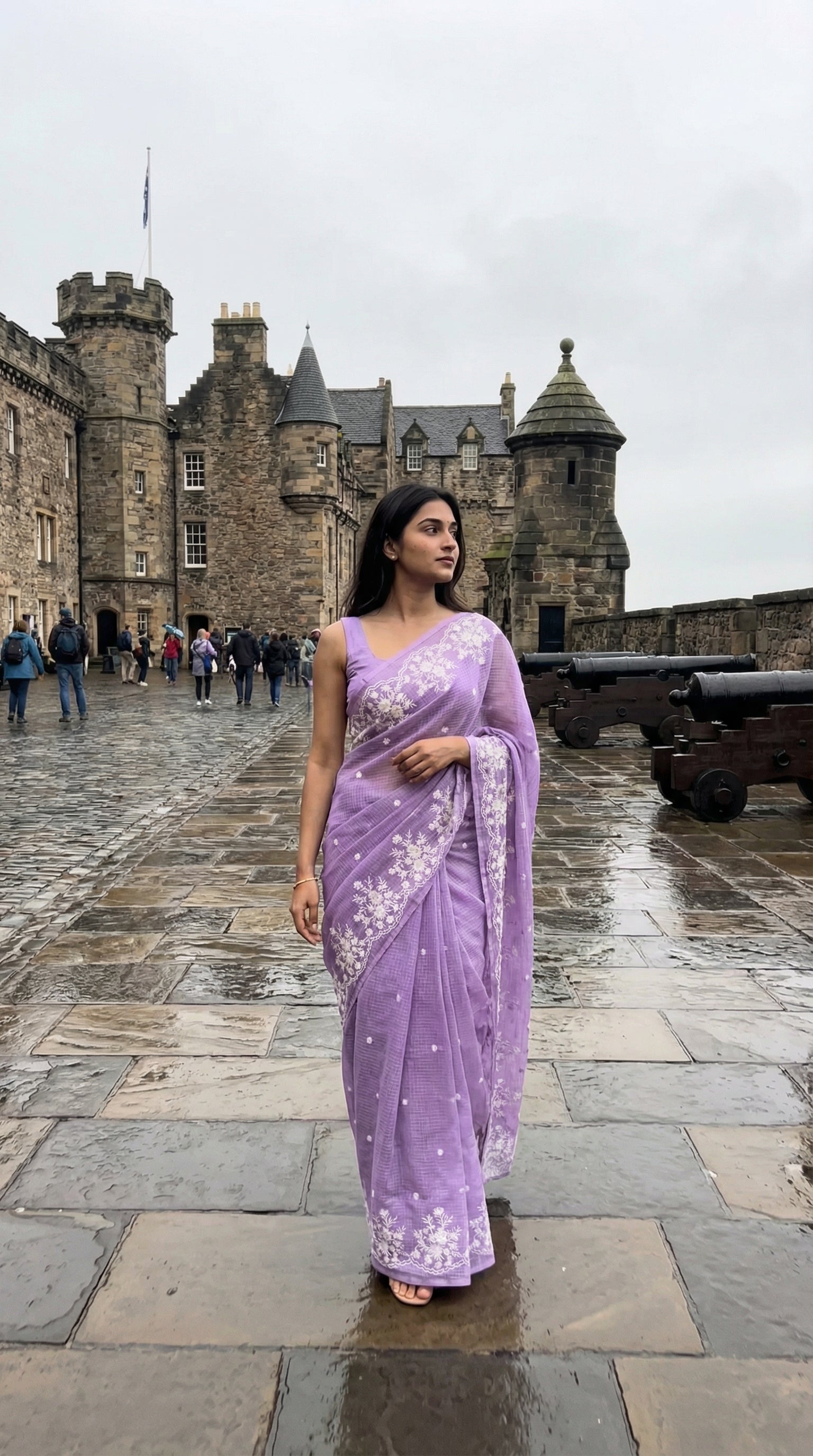 Woman in a purple-resham-kota-cotton-saree, standing in front of a castle.