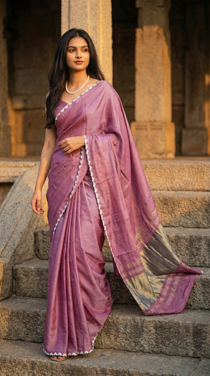 Woman in a rose-pink-modal-silk-saree-lagdi-patta-pallu, standing on stone steps with architectural background