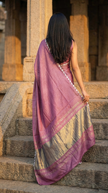 Woman in a rose-pink-modal-silk-saree-lagdi-patta-pallu, climbing stairs on an architectural setup.