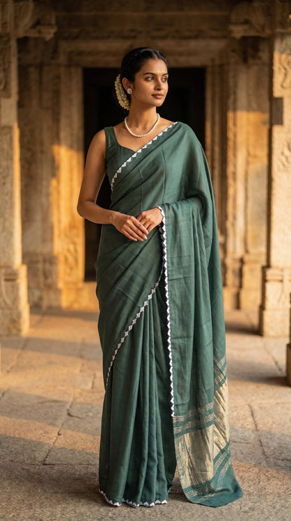 Woman in a sage-green-modal-silk-saree-lagdi-patta-pallu, standing in front of an ancient architectural structure.