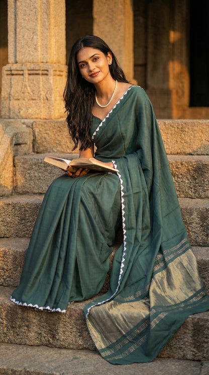 Woman in a sage-green-modal-silk-saree-lagdi-patta-pallu, sitting outdoor on steps.