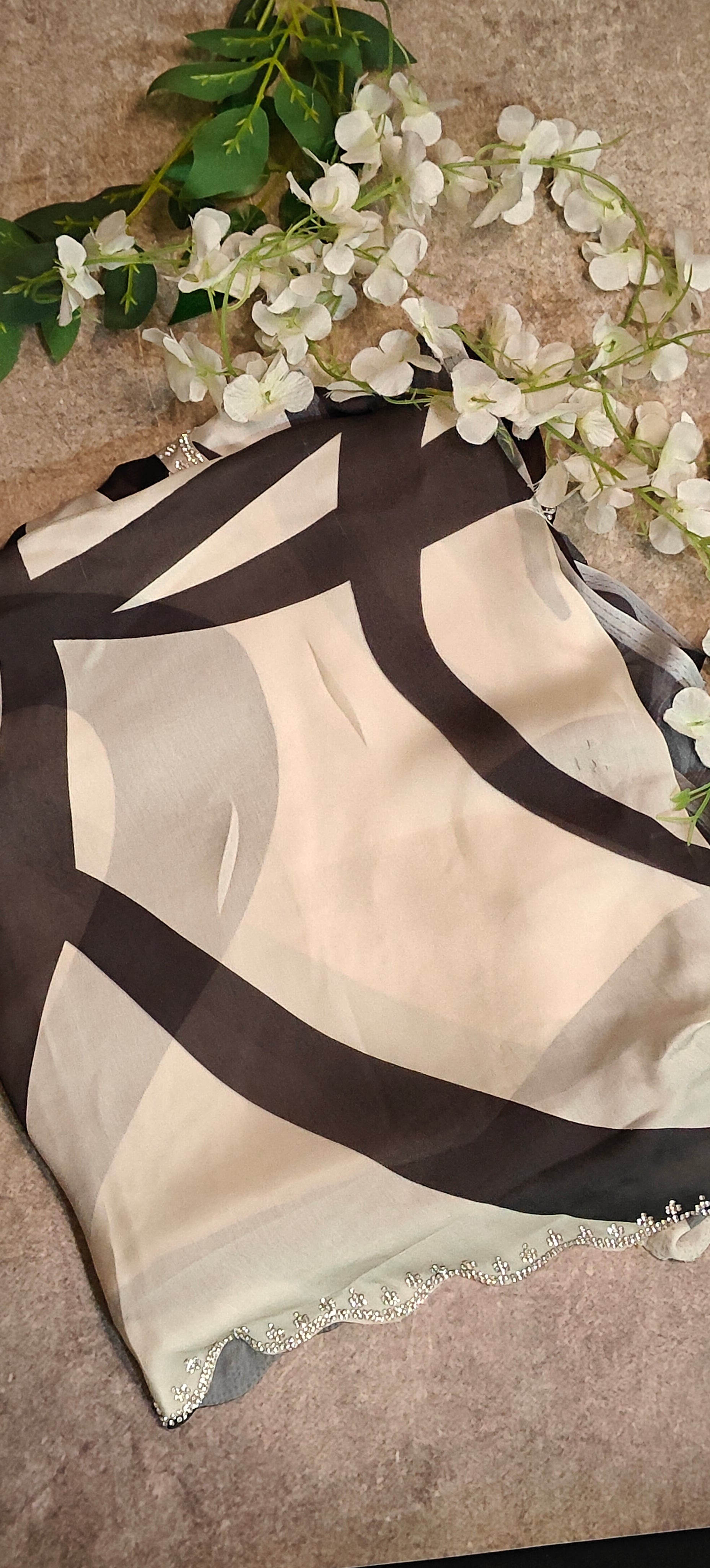 Black satin-georgette saree with abstract line motifs on white base and subtle embellishments, elegant contemporary attire.