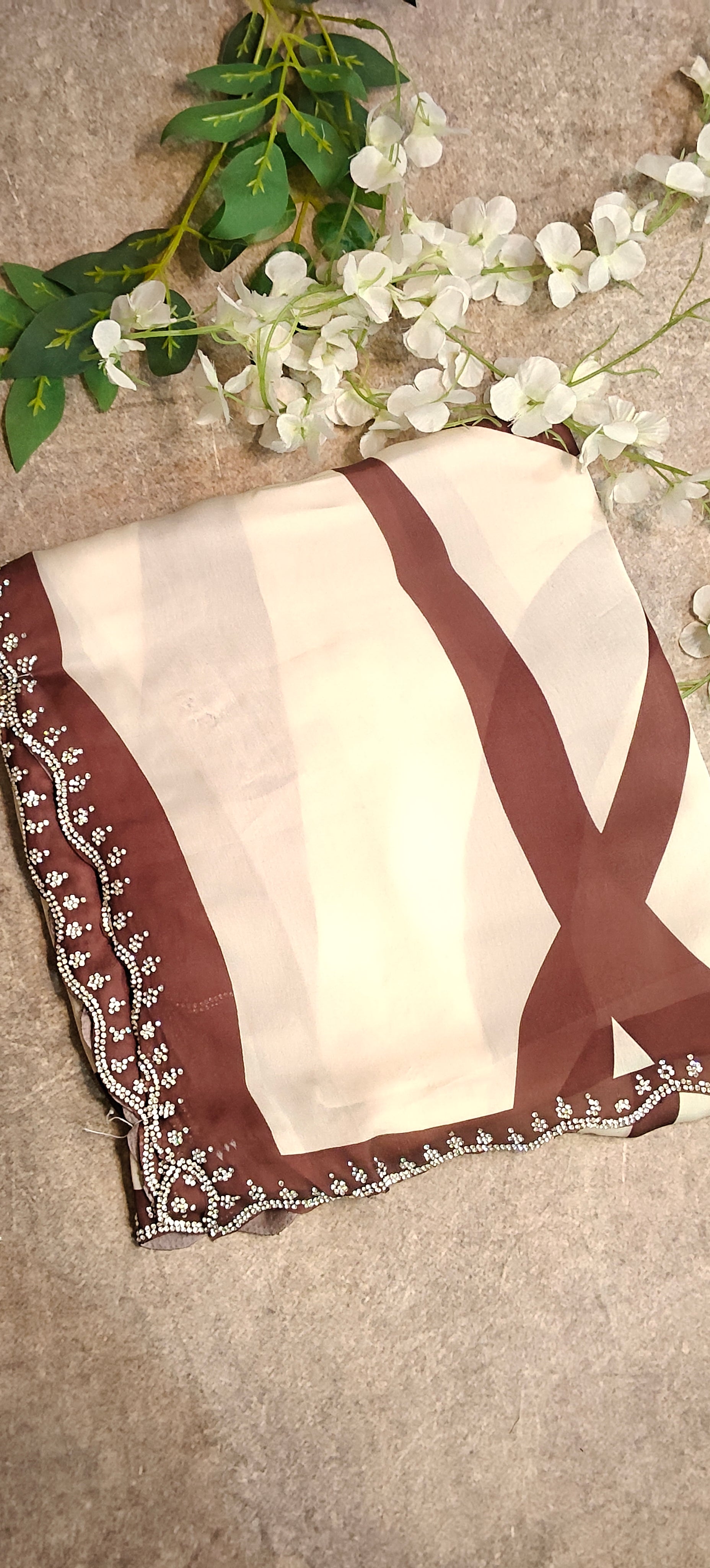 Brown satin-georgette saree with abstract line motifs on white base and subtle embellishments, elegant contemporary attire.