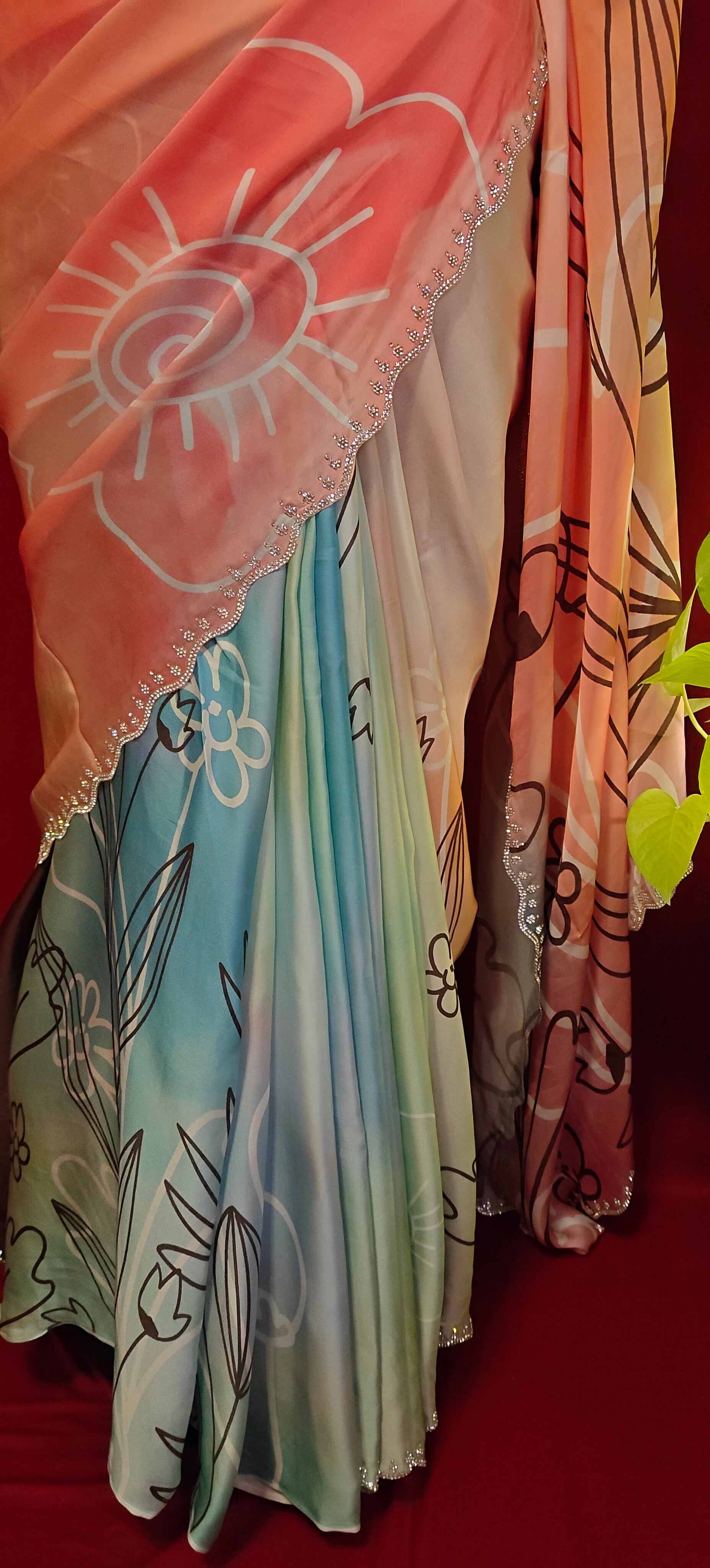 Multicolour satin georgette saree with abstract floral print and silver scalloped border on a mannequin with a red background.
