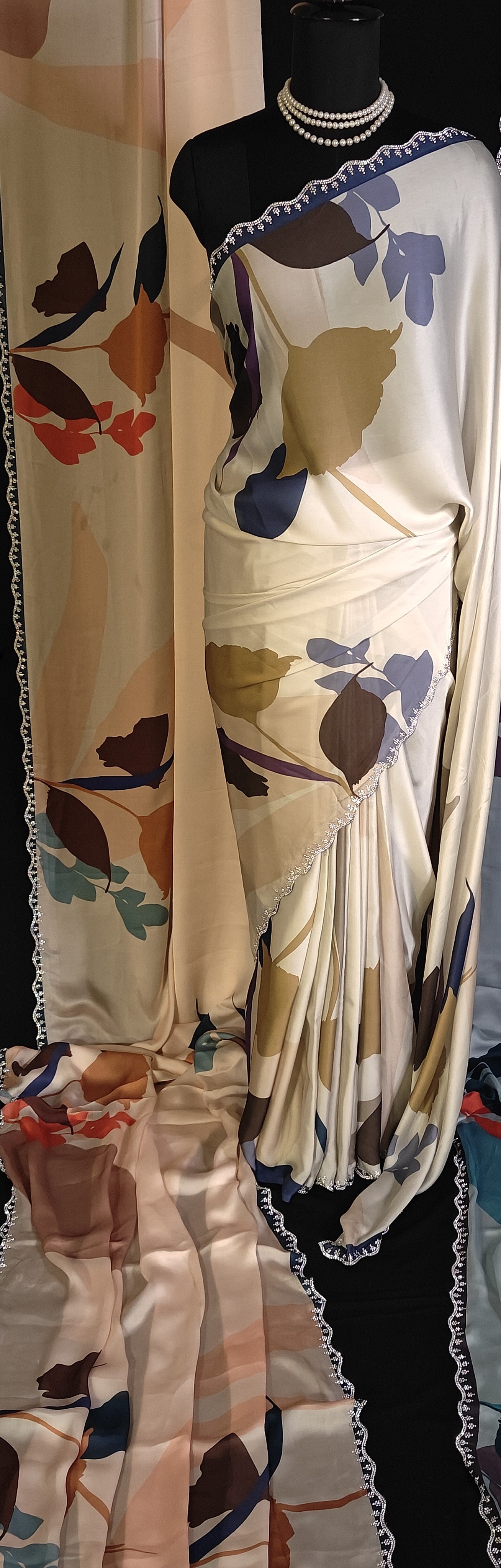 Mannequin wearing a Peach satin-georgette saree featuring bold floral motifs and delicate lace trim, elegant saree for daytime functions.