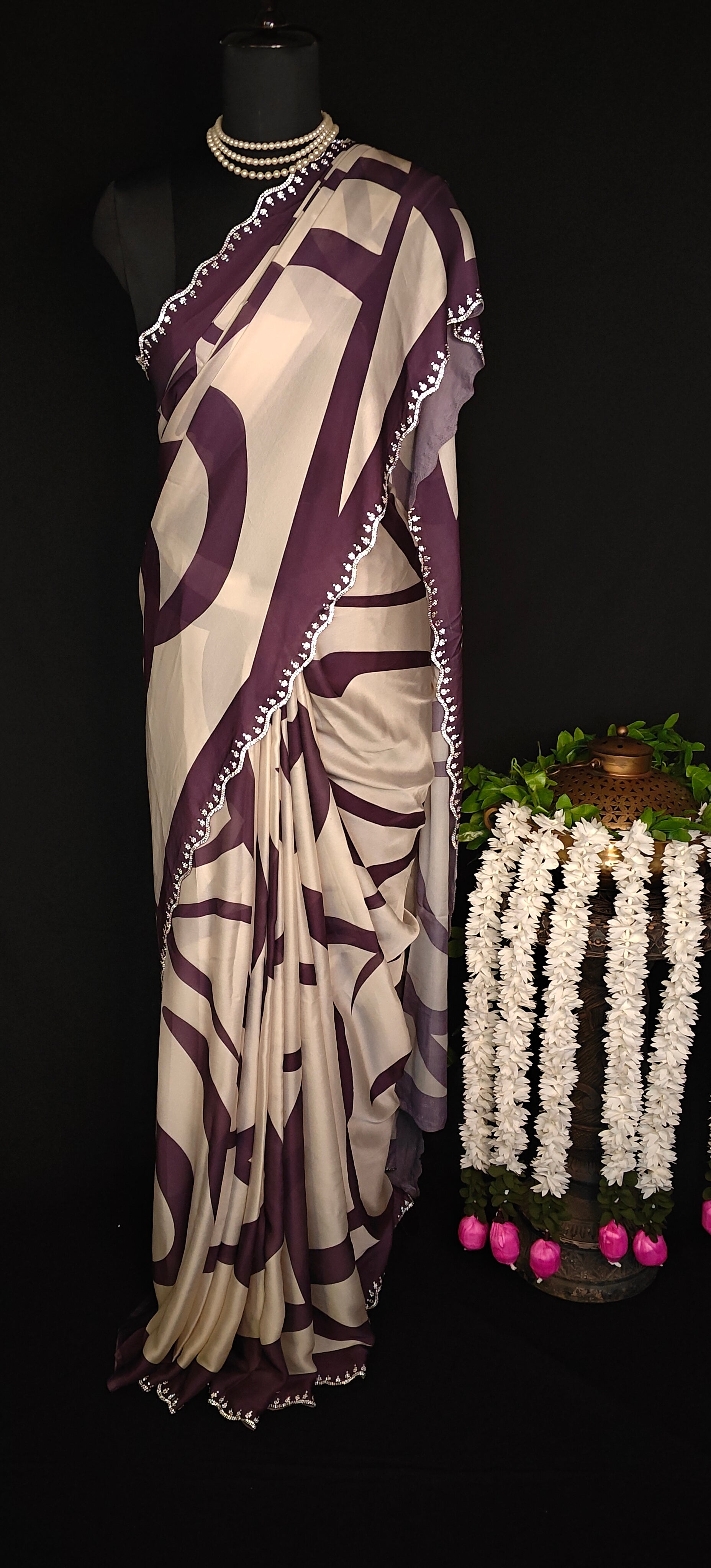 Purple-accented satin-georgette saree featuring abstract line design on white base with delicate border, stylish festive saree.