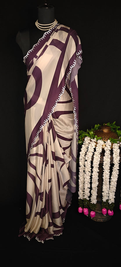 Purple-accented satin-georgette saree featuring abstract line design on white base with delicate border, stylish festive saree.