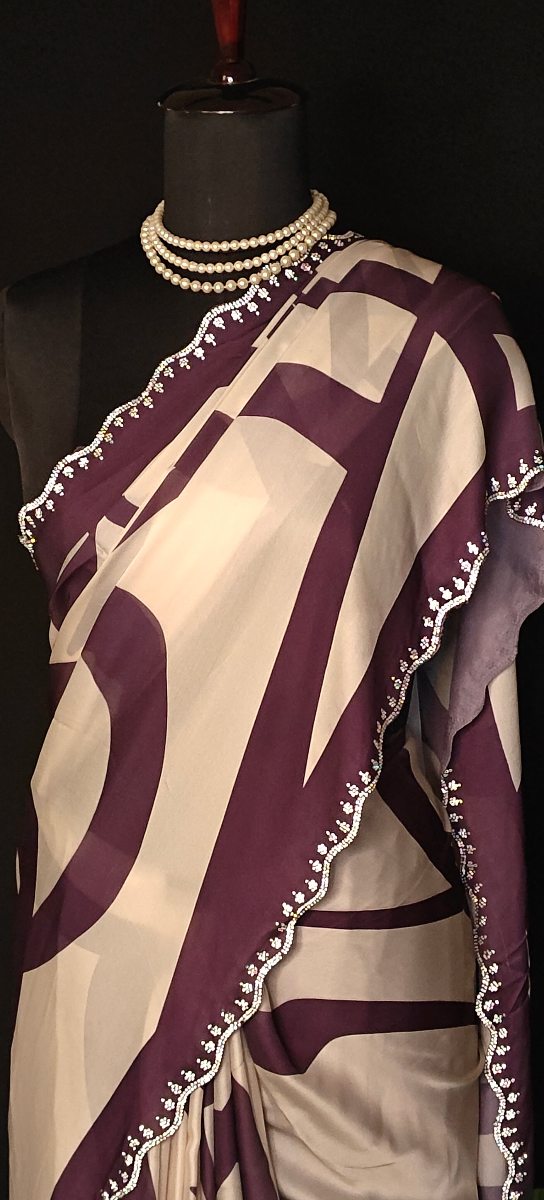 Purple-accented satin-georgette saree featuring abstract line design on white base with delicate border, stylish festive saree.