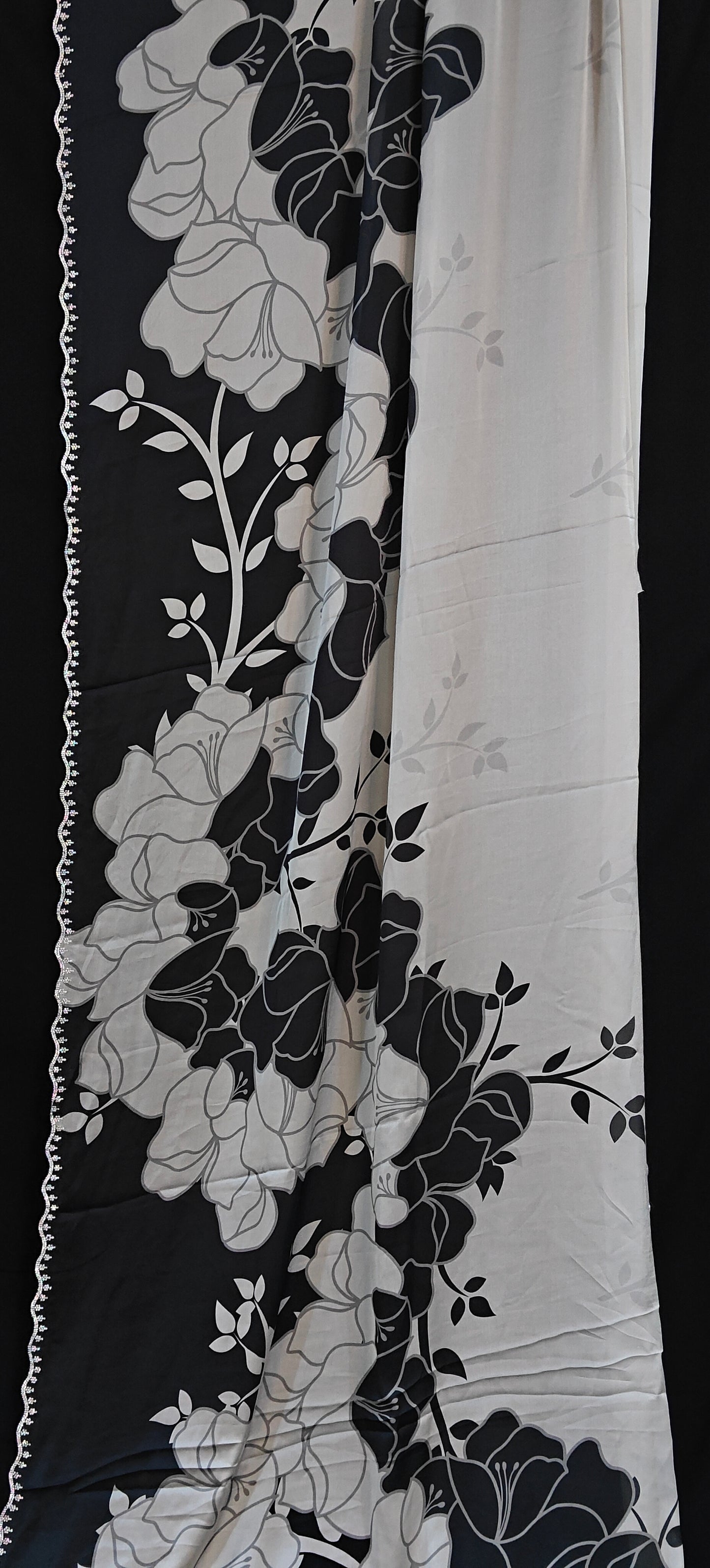 Black satin saree featuring dramatic floral prints and scalloped edge detailing, luxurious Indian attire for celebrations.