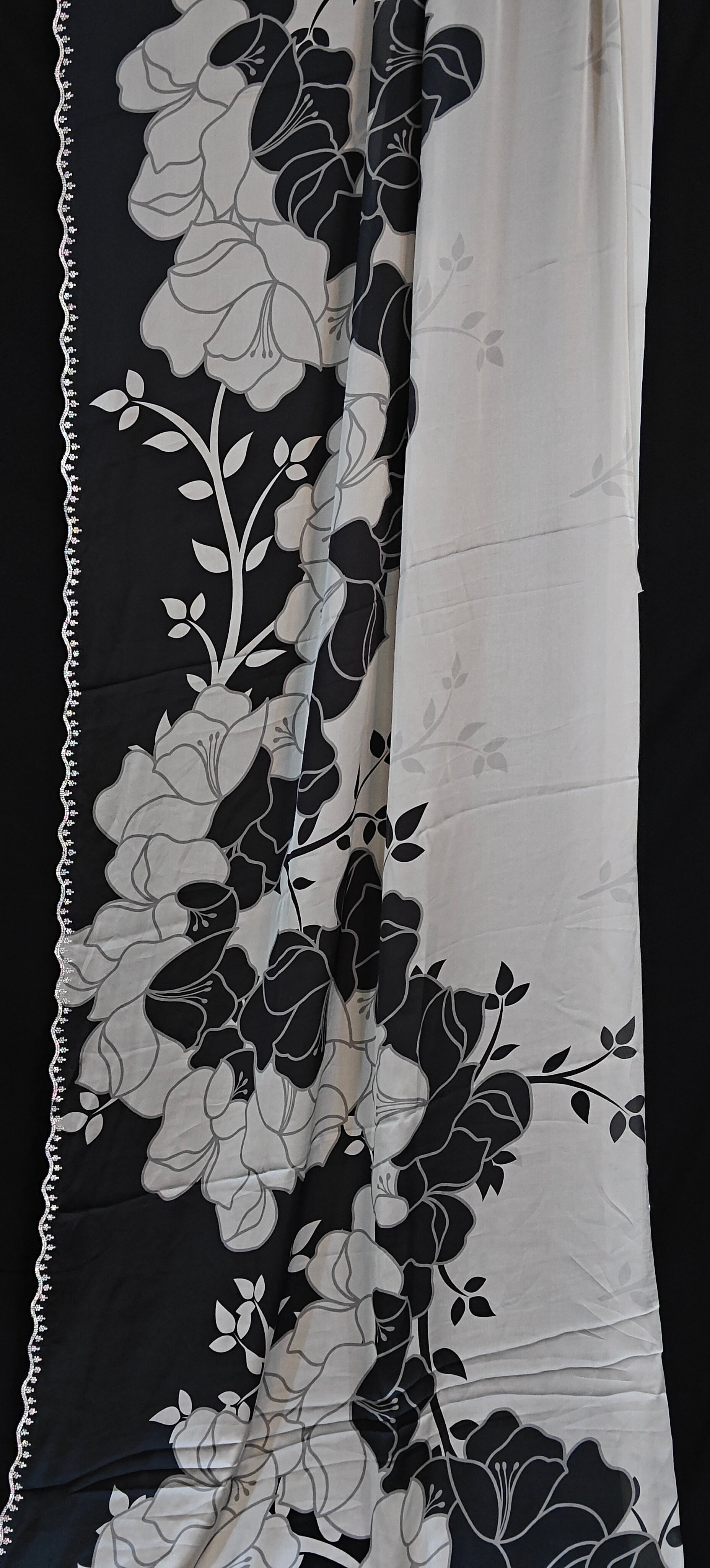 Black satin saree featuring dramatic floral prints and scalloped edge detailing, luxurious Indian attire for celebrations.