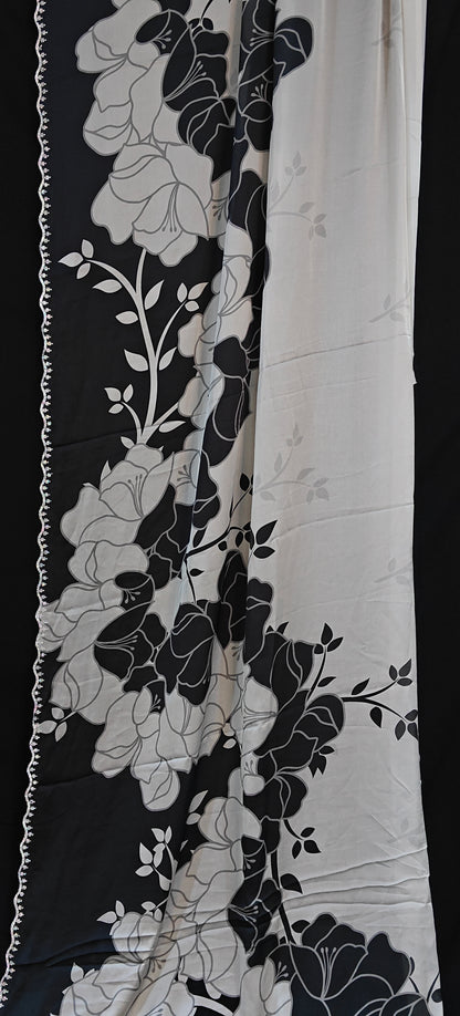 Black satin saree featuring dramatic floral prints and scalloped edge detailing, luxurious Indian attire for celebrations.
