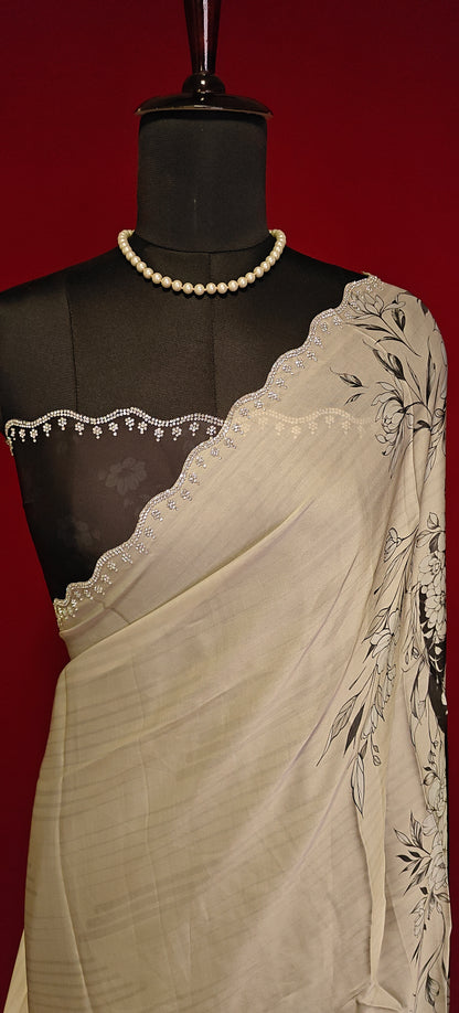 Black and white satin saree with abstract floral print and white pallu, styled on mannequin showcasing the blouse piece in black and silver motif border against red background.
